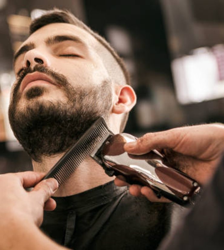 Man getting his beard trimmed with electric razor at hairdesser